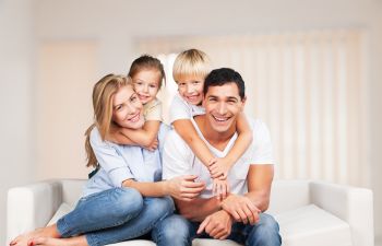 A happy family sitting on a couch in their living room.