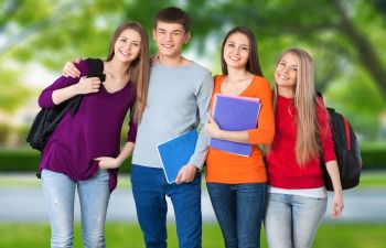 A group of students standing in a park with backpacks.