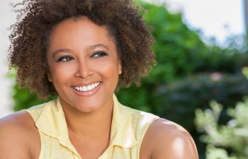 A smiling woman with afro hair outdoors.
