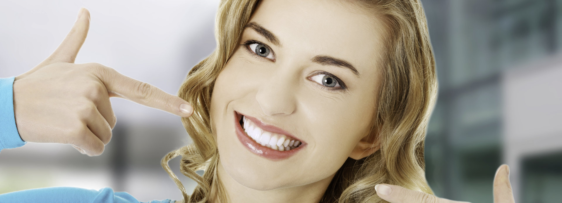 Happy young woman pointing at her beautiful whitened teeth