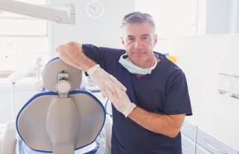 A dentist leaning against a chair in a dental office.