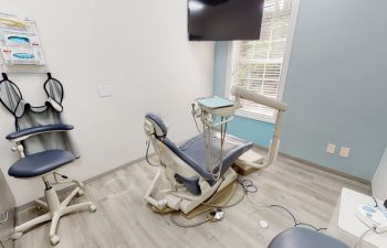 A treatment room with a dental chair and a TV at Buford Family Dental