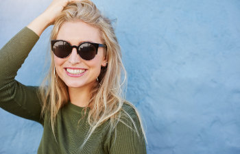 A cheerful blonde woman with sunglasses and perfect smile.