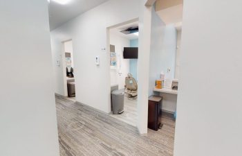 A hallway with white walls and wooden floors at Buford Family Dental.